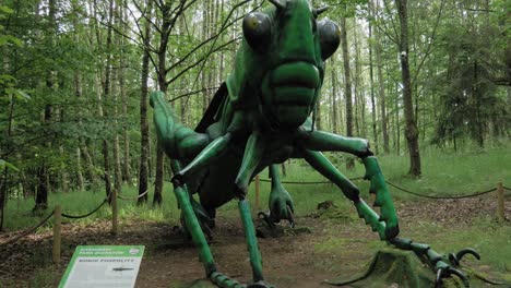 A-giant-green-grasshopper-displayed-in-the-forest-of-the-Kaszubski-Park-Gigantow-in-Poland---wide