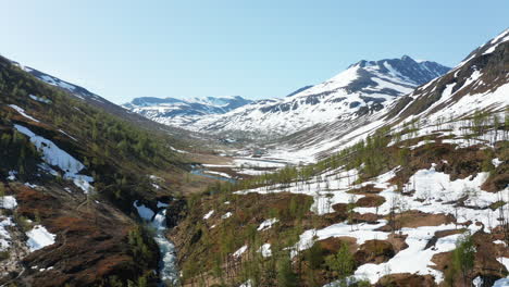 Antena,-Seguimiento-De-Drones-Con-Vistas-A-La-Cima-De-Mohcuhatgaisa,-En-Medio-De-Picos-Nevados,-Cielo-Azul,-En-Un-Día-De-Verano-Brillante-Y-Soleado,-En-Los-Alpes-De-Lyngen,-Norte-De-Noruega