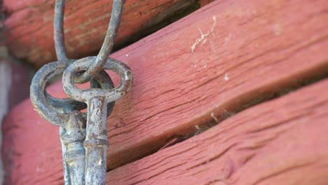 Close-shot-of-old-vintage-keys-on-weathered-old-red-wall,-tilt-down