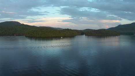 Drone-shot-going-up-and-down-on-a-beautiful-lake-and-forest-at-colorful-dusk-in-the-Eastern-Township