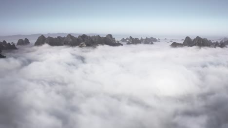 Aerial:-mountaintops-rising-above-clouds,-low-cloud-cover-in-mountain-valley