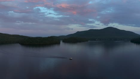 Drone-following-a-lonely-boat-on-a-lake-at-dusk-with-beautiful-colors-in-the-Eastern-Township,-Quebec,-Canada