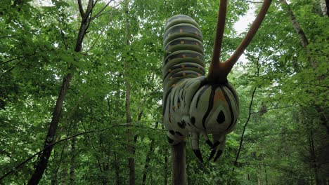 Large-Caterpillar-Model-Against-The-Green-Trees-In-The-Forest-At-The-Kashubian-Park-Of-Giants,-Strysza-Buda,-Poland