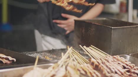 Yatai-Food-Vendor-Selling-Grilled-Squid-Skewers-During-Yoiyama-Festival-At-The-Gion-Matsuri-Festival-Night-In-Kyoto,-Japan---close-up-slowmo