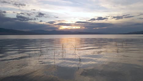 Beautiful-sunset-reflected-on-Utah-Lake,-drone-flying-low-over-the-water