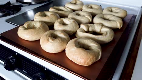 A-tray-of-homemade-bagels-on-baking-tray-in-a-home-kitchen,-pull-back