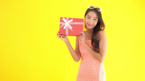 Pretty-asian-female-showing-birthday-gift-box,-Slow-motion-of-stylish-girl,-isolated-on-yellow-background
