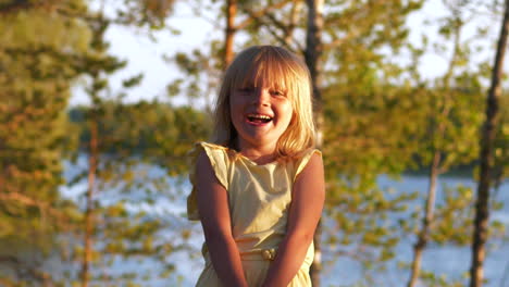 Portrait-of-Young-blonde-girl-showing-authentic-happiness-and-pure-joy,-lake-background-at-sunset