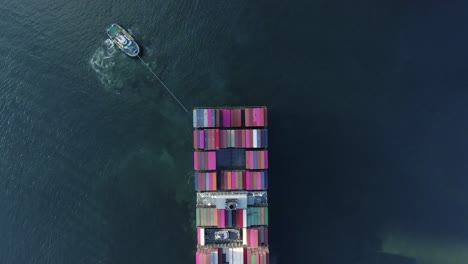 Tugboat-manoeuvring-a-large-empty-Container-Ship-into-Hong-Kong-port,-Aerial-view