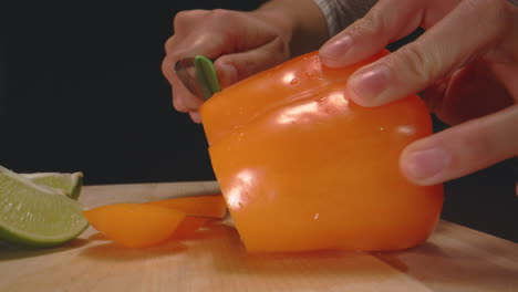 Woman's-hands-cutting-orange-bell-pepper-with-paring-knife