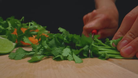 Woman's-hands-slicing-cilantro-on-wooden-cutting-board