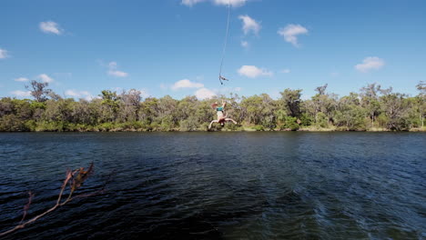 Low-angle-view-follow-a-man-who-dives-with-the-rope-swing-in-the-river