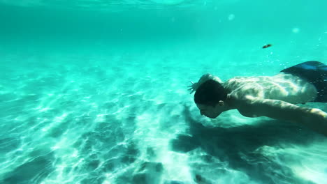 Young-man-gets-under-crystal-clear-water-in-Sardinia,-slow-motion