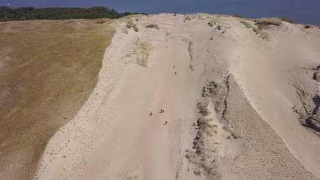 High-angle-aerial-shot-of-tourists-walking-across-the-Grey-Dunes-on-the-Curonian-Split-in-Lithuania