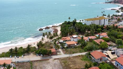 Aerial-drone-circling-shot-of-the-small-beach-town-of-Tabatinga-near-Joao-Pessoa-in-Northern-Brazil-with-small-sand-roads,-beach-homes,-and-tropical-foliage-on-a-warm-summer-day