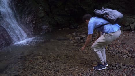Ein-Männlicher-Wanderer-Wäscht-Sein-Gesicht-Im-Teich-Neben-Einem-Kleinen-Wasserfall-In-Japan---Mittenschuss
