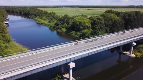 Eine-Gruppe-Von-Radfahrern-überquert-Eine-Brücke-über-Einen-Fluss-In-Der-Litauischen-Landschaft