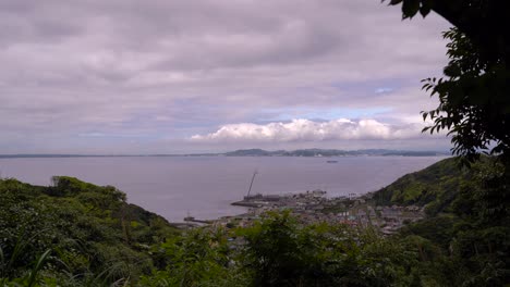 Beautiful-View-Out-On-Harbor-Town-And-Ocean-In-Between-Dense-Trees-On-A-Cloudy-Day---Wide-Shot