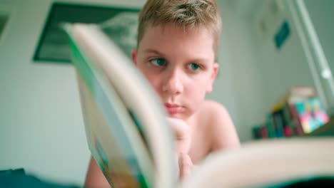 The-footage-in-high-definition-of-a-kid-lying-and-reading-a-book,-turning-pages