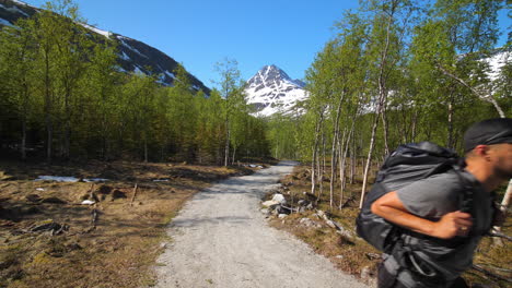 Man-hiking-on-Piltiridalen-mountain-trail,-in-middle-of-snowy-peaks,-on-a-sunny,-summer-day,-in-the-Lyngen-alps,-North-Norway