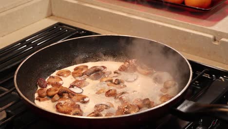 Woman-adding-cream-to-sauted-button-mushrooms-and-stirring-to-make-a-light-cream-sauce
