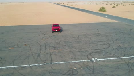 Red-truck-parked-on-tarmac-road-before-desert