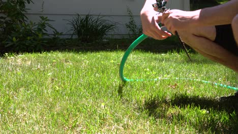 A-man-unhooks-an-old-school-mechanical-sprinkler-in-the-heat-of-summer