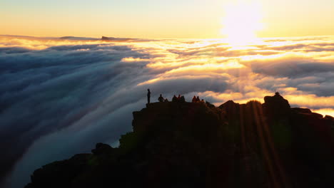 Aerial-orbit,-drone-shot-around-hikers,-on-the-summit-of-the-on-Mount-Hassell-Mountain,-above-clouds,-during-sunset,-in-West-Australia