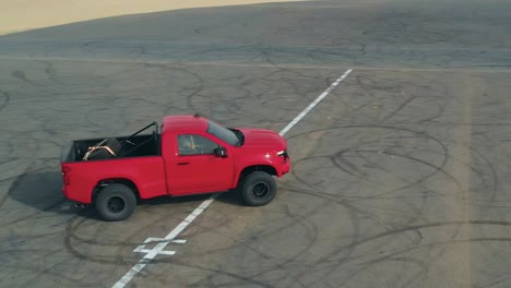 Racing-truck-driving-on-tarmac-road-in-the-desert,-drone-orbiting