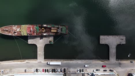 Top-down-aerial-view-of-an-industrial-harbour-with-a-cargo-ship-in-a-dock