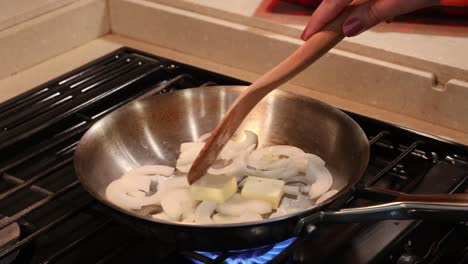 Melting-butter-in-a-skillet-with-sliced-sweet-onions-on-a-tiny-stove
