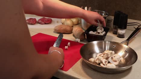 Woman-slicing-button-mushrooms-using-a-Japanese-chef-knife-and-a-red-cutting-board