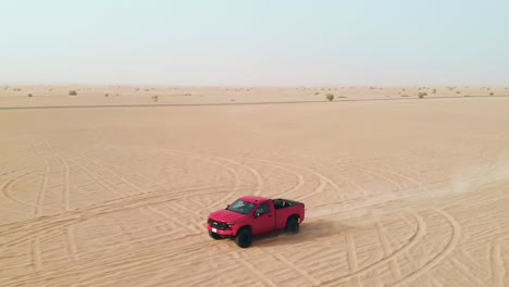 Off-raod-truck-driving-through-the-flat-desert,-drone-track-backwards