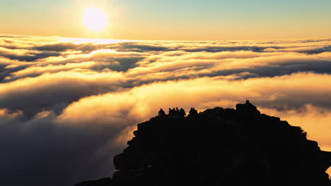 Aerial,-drone-view-orbiting-around-hikers,-on-the-summit-of-the-on-Mount-Hassell-Mountain,-above-clouds,-during-sundown,-in-West-Australia