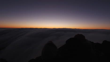 Trekkers-hugging-and-enjoying-the-sunset,-above-clouds-on-a-mountain-summit,-in-Hassell-National-Park,-West-Australia