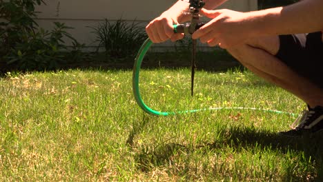 A-man-hooks-up-an-old-fashioned-mechanical-sprinkler-in-the-heat-of-summer