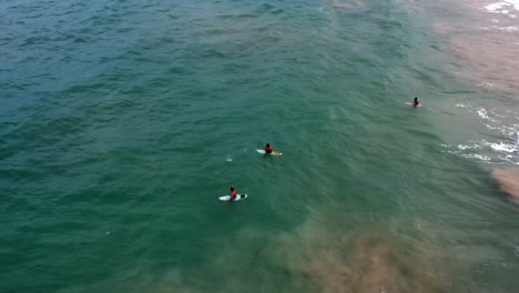Luftdrohnenaufnahme-Fortgeschrittener-Surfer,-Die-An-Einem-Warmen-Sommertag-Am-Berühmten-Tropischen-Strand-Coqueirinhos-In-Der-Nähe-Von-Joao-Pessoa-Im-Norden-Brasiliens-Sitzen-Und-Warten