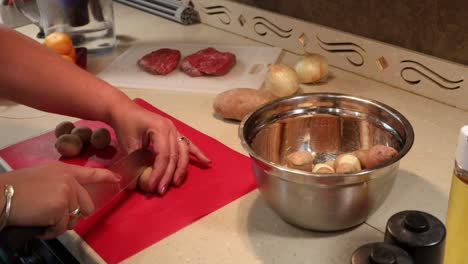 Woman-quartering-baby-potatoes-and-putting-the-pieces-into-a-stainless-steel-bowl