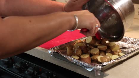 Close-up-of-woman-putting-sliced,-oiled-and-seasoned-baby-potatoes-onto-a-pan-for-roasting-in-an-RV-kitchen