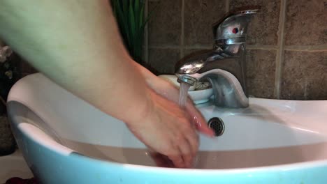 Nahaufnahme-Des-Gründlichen-Händewaschens-Mit-Weißer-Seife-über-Ovalem-Waschbecken-Und-Einhebelmischer-Im-Badezimmer-Mit-Braunen-Kalksteinfliesen-In-4k