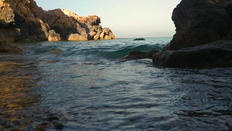 Close-up-of-waves-current-against-rocky-shore-on-sunny-day-in-Sardinia,-Italy,-summer-vacation