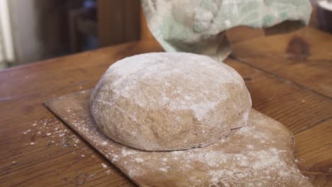 Placing-Sourdough-On-A-Wooden-Board-In-The-Kitchen-For-Resting---close-up-slowmo