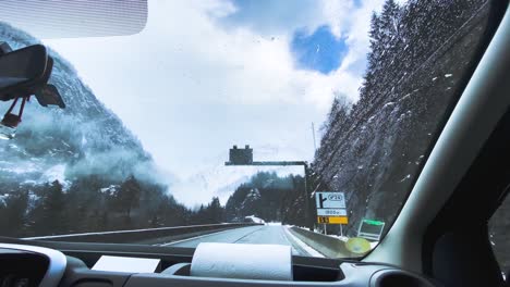 Car-Driving-On-The-Snowy-Road-To-Chamonix,-France-With-Wipers-Cleaning-The-Windshield-For-Safety---rolling-shot
