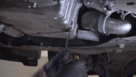Draining-used-old-engine-oil-from-sump-in-car-workshop-by-a-mechanic