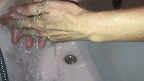 Faceless-closeup-of-thorough-hand-washing-in-white-bathtub-sink-in-4K
