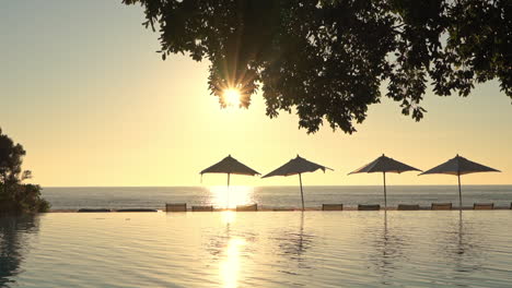 Goldenes-Sonnenlicht-Scheint-über-Den-Himmel,-Das-Meer-Und-Den-Pool-Eines-Luxuriösen-Tropischen-Resorts