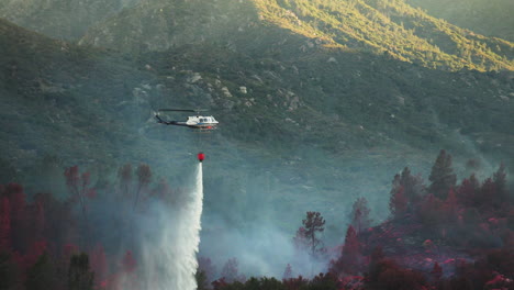 Firefighting-helicopter-bucket-dropping-fire-retardant-over-bush-fire