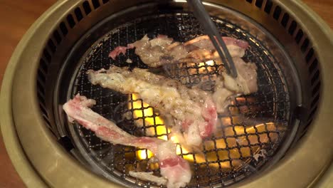 Shabu-shabu,-Japanese-nabemono-hotpot-dish-of-thinly-sliced-meat,-cooking-on-grill-with-hot-flames-and-fire,-above-static-close-up