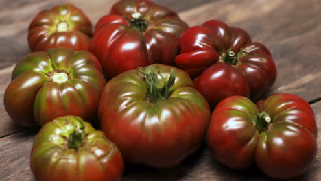 Cherokee-purple-homegrown-tomatoes-on-wooden-table-close-up-panning-shot-across-the-fruit