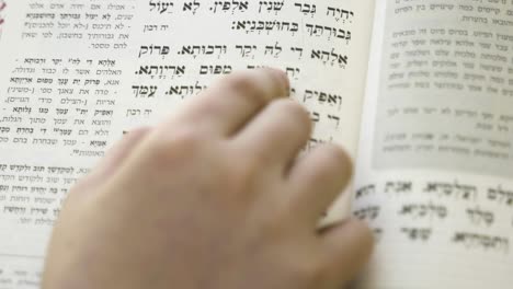 Un-Niño-Leyendo-Un-Libro-Sagrado-Hebreo,-Sigue-La-Lectura-Con-El-Dedo,-Libro-Judío-De-Oración
